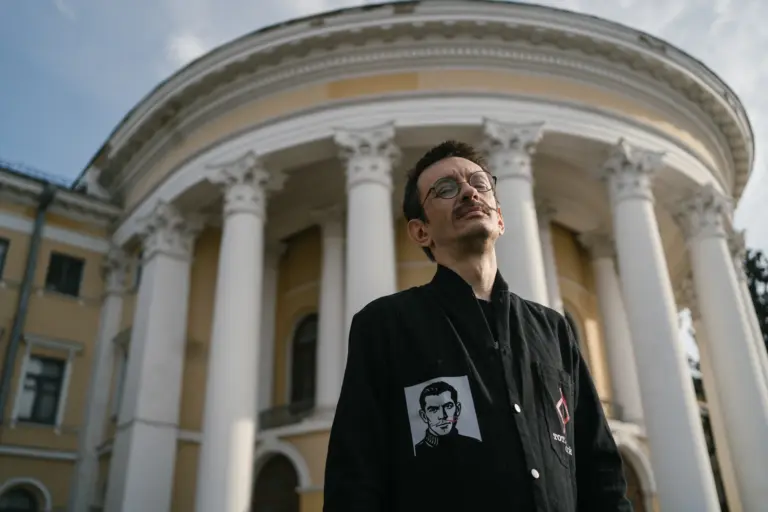 Marjan Pyrih, Musiker, Gründer der Bands „Hytsch Orkestr“ und „Pyrih i Batih“, Mitbegründer des Musikprojekts „Tschystyj Tschetwer“ (gemeinsam mit seiner Ehefrau Jelysaweta Pyroschok gegründet), Künstler; seit dem Sommer 2025 Militärangehöriger. Im Hintergrund der Oktoberpalast, in dem die sowjetische Geheimpolizei NKWD zwischen 1934 und 1941 ukrainische Intellektuelle erschoss. Die Gedichte von dort Erschossenen vertont Marjan Pyrih mit seiner Band. Kyjiw. Oktober 2025. Projekt „Wie weiter?“. Foto: Chrystyna Kulakovska.